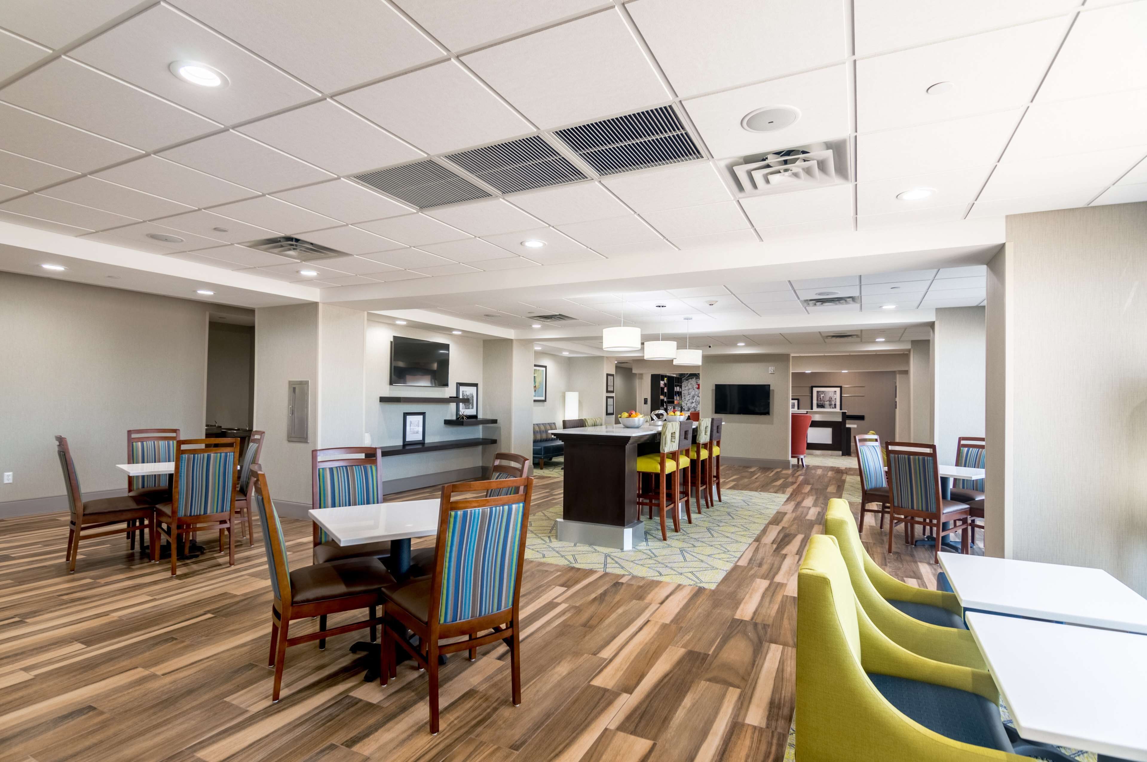 A modern dining area with wooden flooring, striped chairs, and a central island with a bar.