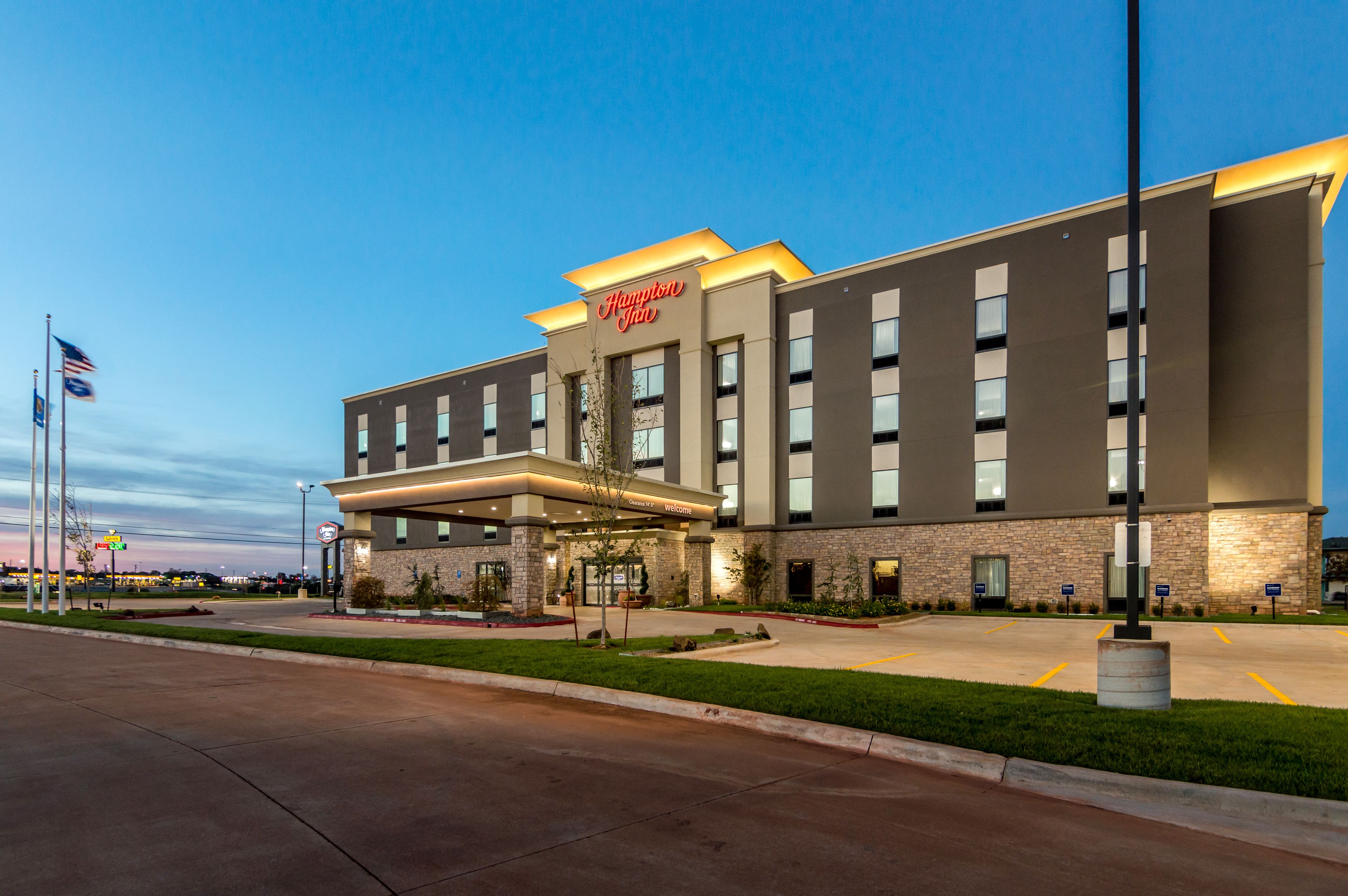 A Hampton Inn hotel with a modern exterior, a well-lit entrance, and a parking lot.