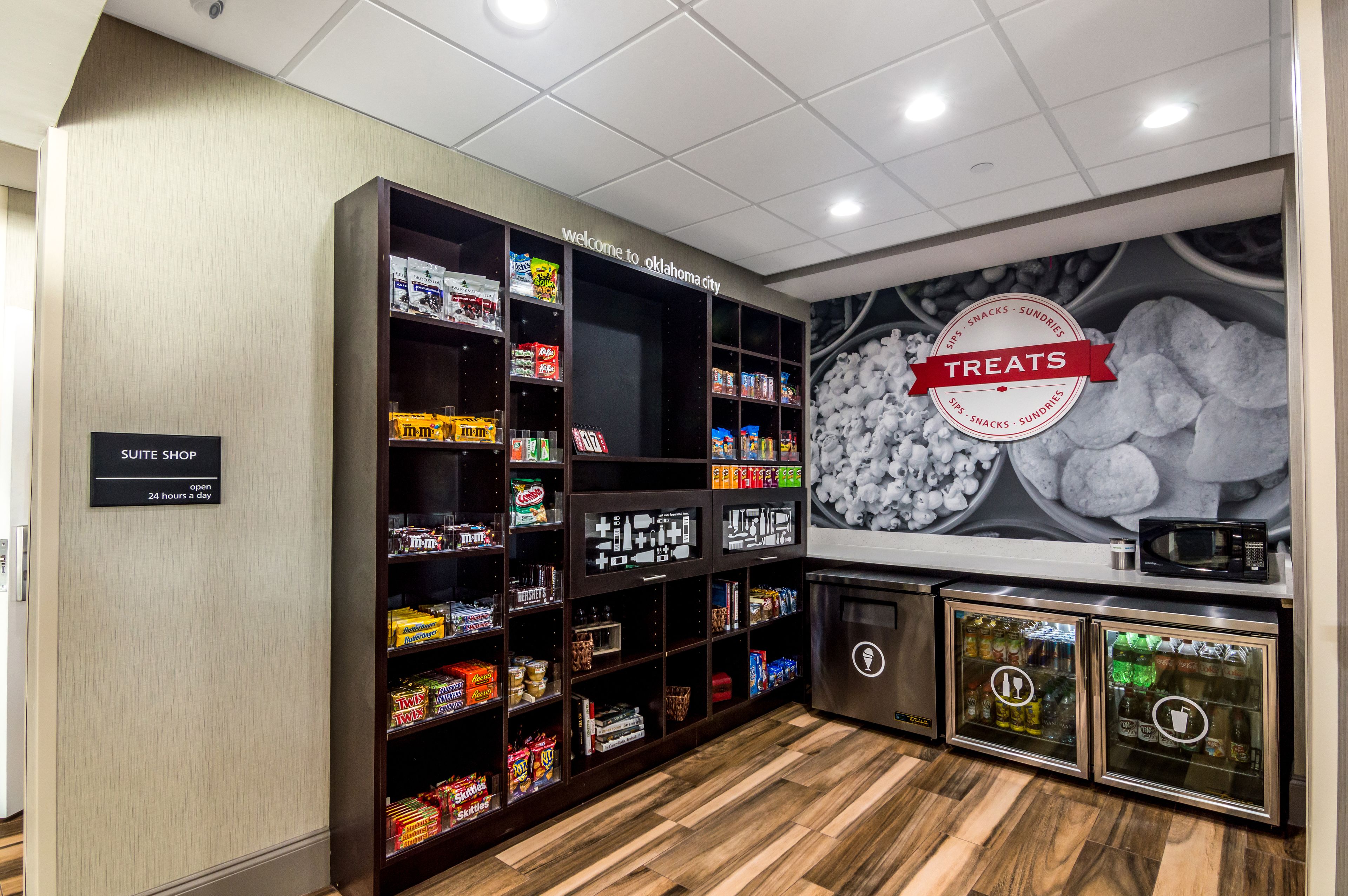 Una tienda con suites, estantes llenos de bocadillos y dulces, un microondas y un refrigerador.