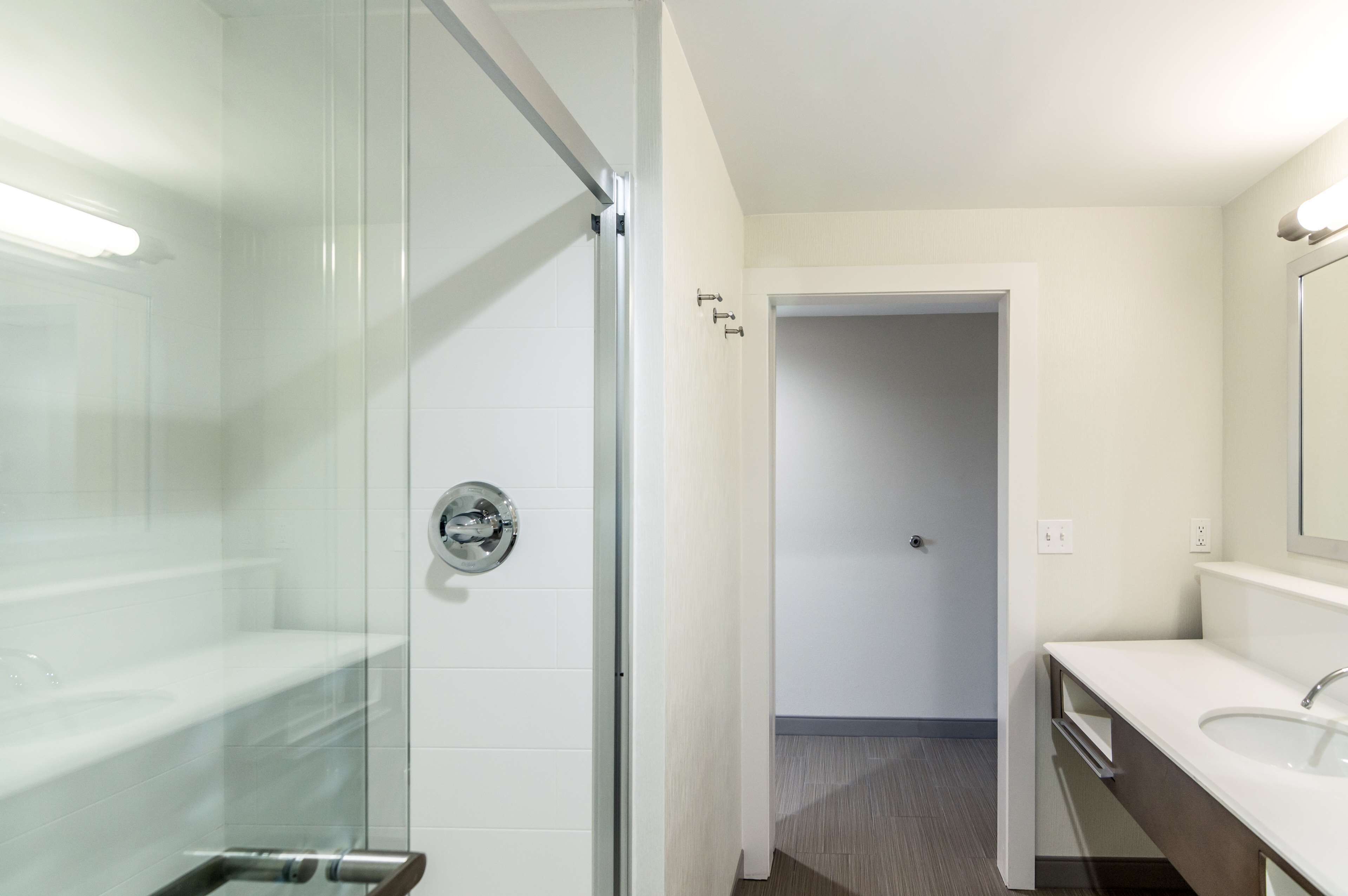 A modern bathroom with a glass shower enclosure, a white sink, and a mirror.