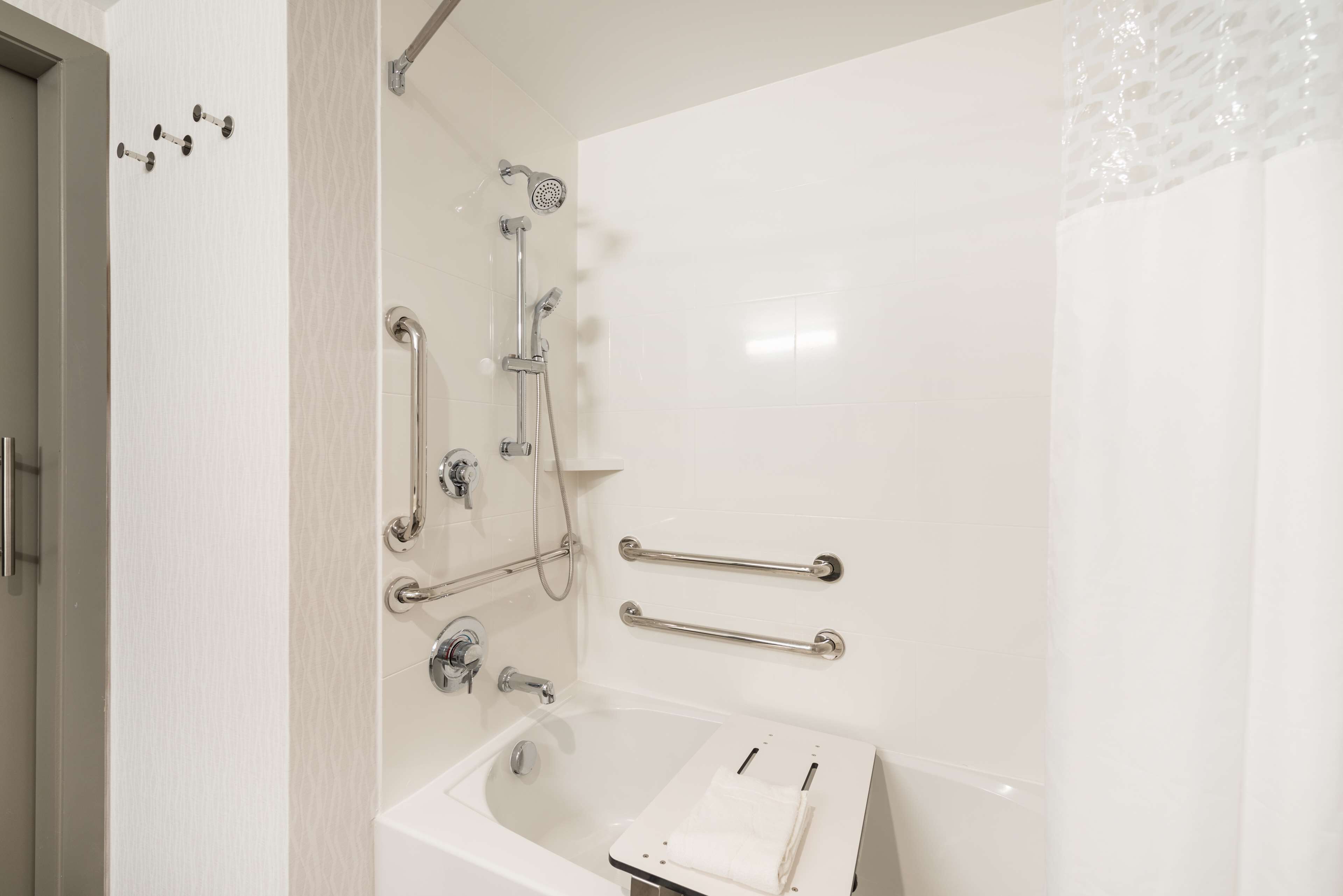 A modern bathroom with a bathtub, shower, and grab bars.