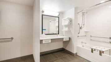 Un baño moderno con ducha, un lavamanos con espejo y un perchero para toallas.