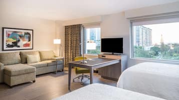 A hotel room with a sofa, a desk, a television, and a bed.