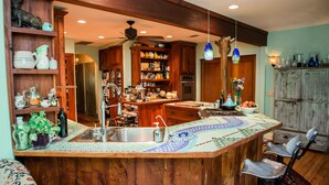 A kitchen with wooden cabinets, a central island with a sink, and a ceiling fan. - Park Lane Guest House (Austin)