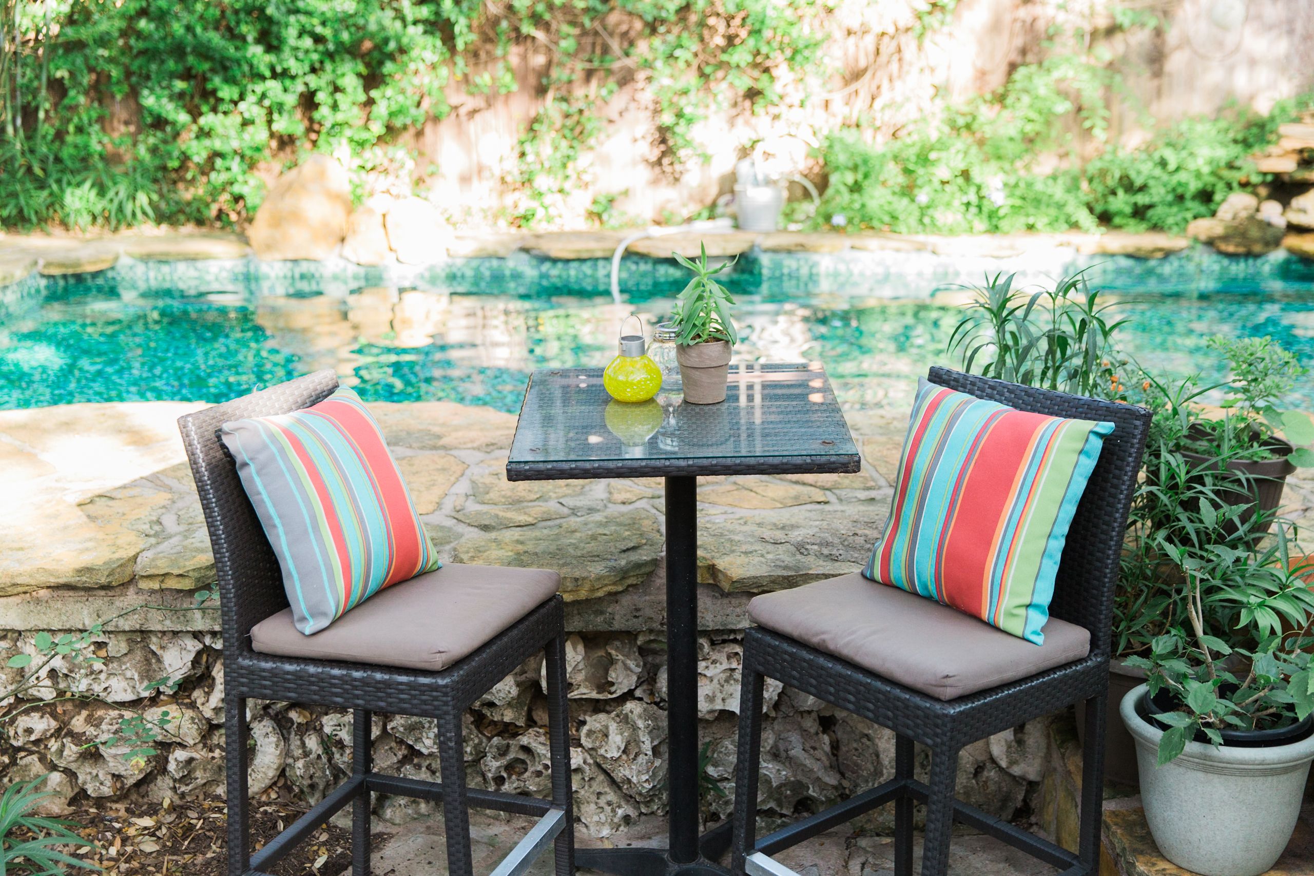 Une terrasse avec deux fauteuils en osier, une petite table et une plante en pot.