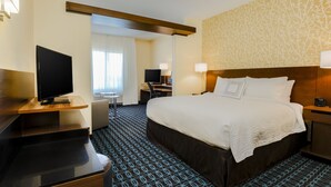 A hotel room with a large bed, a desk with a flat-screen TV, a chair, and a desk lamp. - Fairfield by Marriott Inn & Suites Wheeling at The Highlands (Triadelphia)