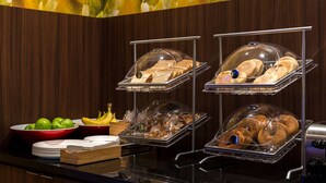 A buffet setup with various food items like bread, fruits, and pastries. - Fairfield by Marriott Inn & Suites Wheeling at The Highlands (Triadelphia)