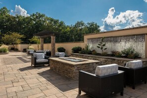 An outdoor patio with stone flooring, wicker furniture, a fire feature, and a tiled wall with plants. - Courtyard by Marriott Nashville Mount Juliet (Mount Juliet)