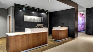 A reception area with two wooden reception desks, a large abstract artwork on the wall, and a modern light fixture. - Courtyard by Marriott Nashville Mount Juliet (Mount Juliet)