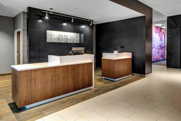 A reception area with two wooden reception desks, a large abstract artwork on the wall, and a modern light fixture. - Courtyard by Marriott Nashville Mount Juliet (Mount Juliet)