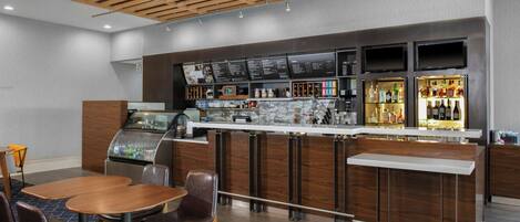 A modern bar area with a self-service beverage dispenser, a menu board, and a selection of liquor bottles.