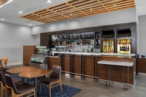 Zona bar moderna con distributore automatico di bevande, bacheca dei menu e selezione di bottiglie di liquore.