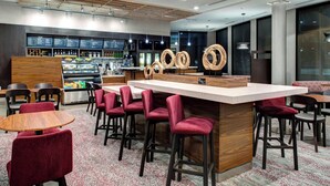 A modern restaurant with a central bar area, seating arrangements, and a menu display. - Courtyard by Marriott Nashville Mount Juliet (Mount Juliet)