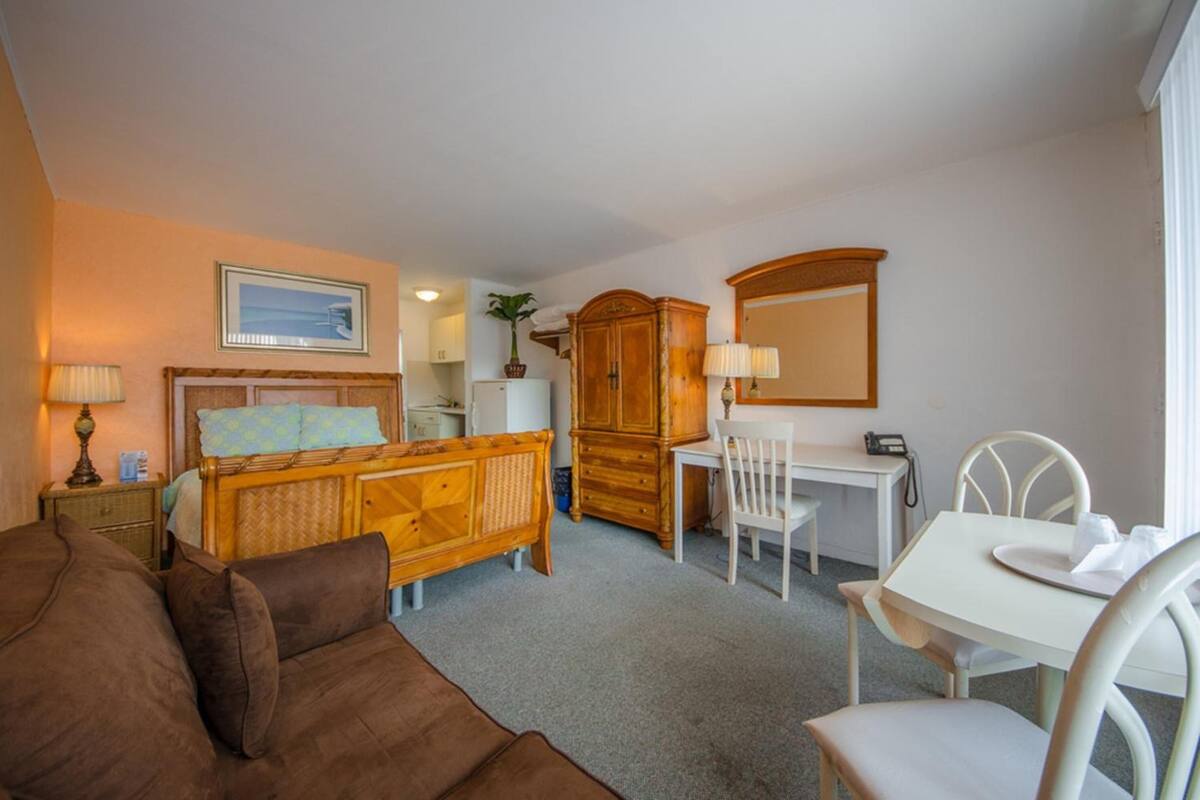 A hotel room with a bed, a desk, a chair, a wardrobe, and a mirror.