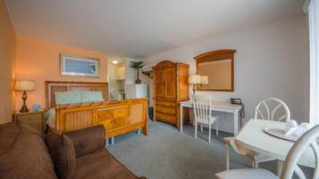 A hotel room with a bed, a desk, a chair, a wardrobe, and a mirror.