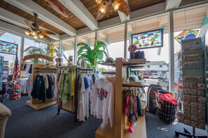 A clothing store with racks of clothes, a large plant, and a view of the street outside. - Tangiers Motel (Wildwood Crest)