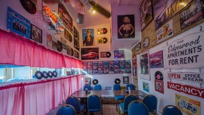 A diner with vintage decor, including vinyl records and classic car posters. Tables and blue chairs are arranged for dining. - Tangiers Motel (Wildwood Crest)