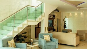 A spacious living area with a staircase, light blue sofas, a coffee table, and a chandelier. - Hotel Parque Del Sol (Montería)