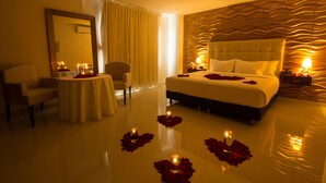 A hotel room with a large bed, a round table with candles, and a chair. - Hotel Parque Del Sol (Montería)