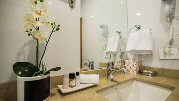 Un baño con lavabo, espejo y perchero para toallas.