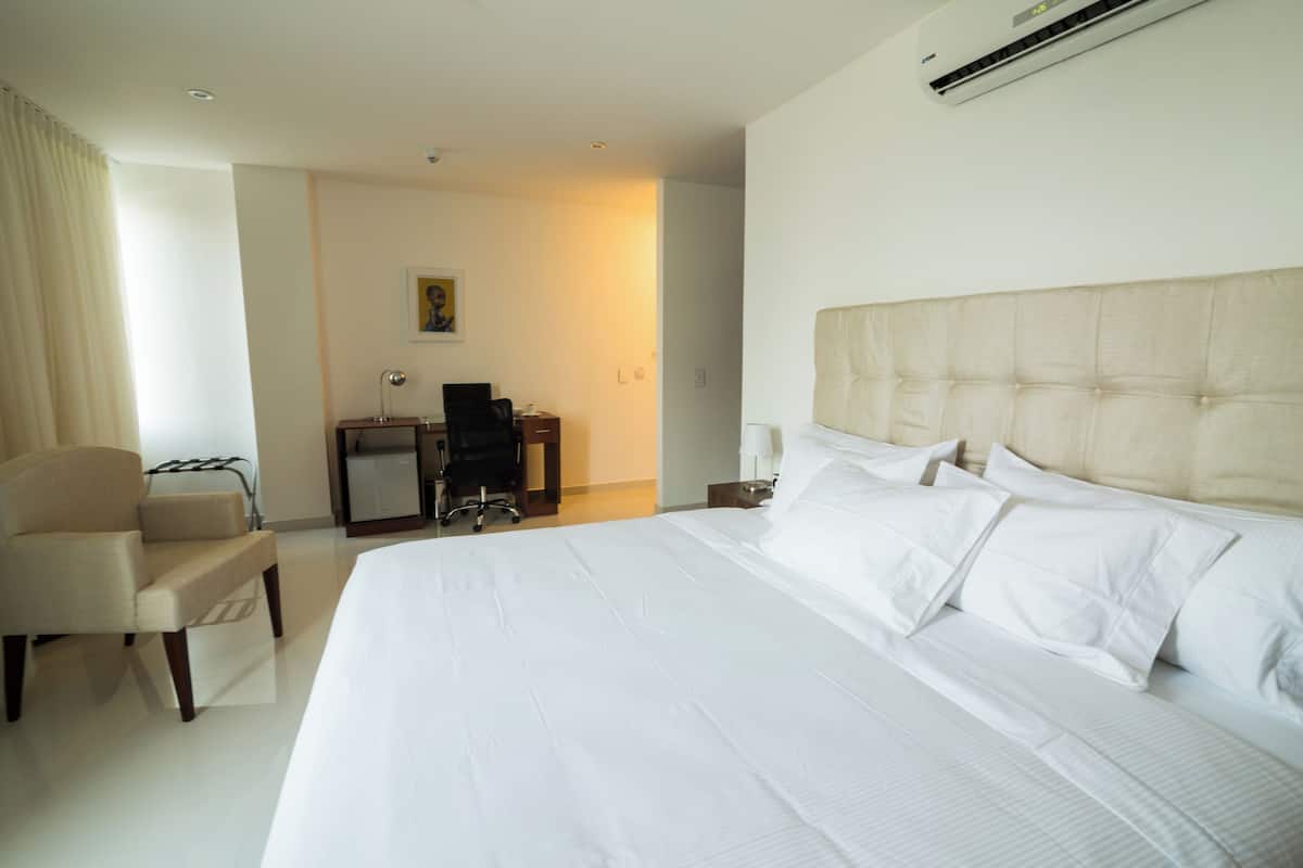Una habitación de hotel con una cama grande, una silla, un escritorio y una lámpara.