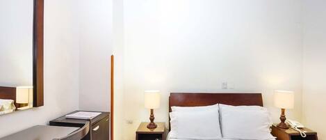 A hotel room with a bed, two bedside tables, a desk, and a chair.