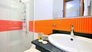 Une salle de bain avec une douche à parois de verre, un lavabo blanc et un miroir au-dessus.