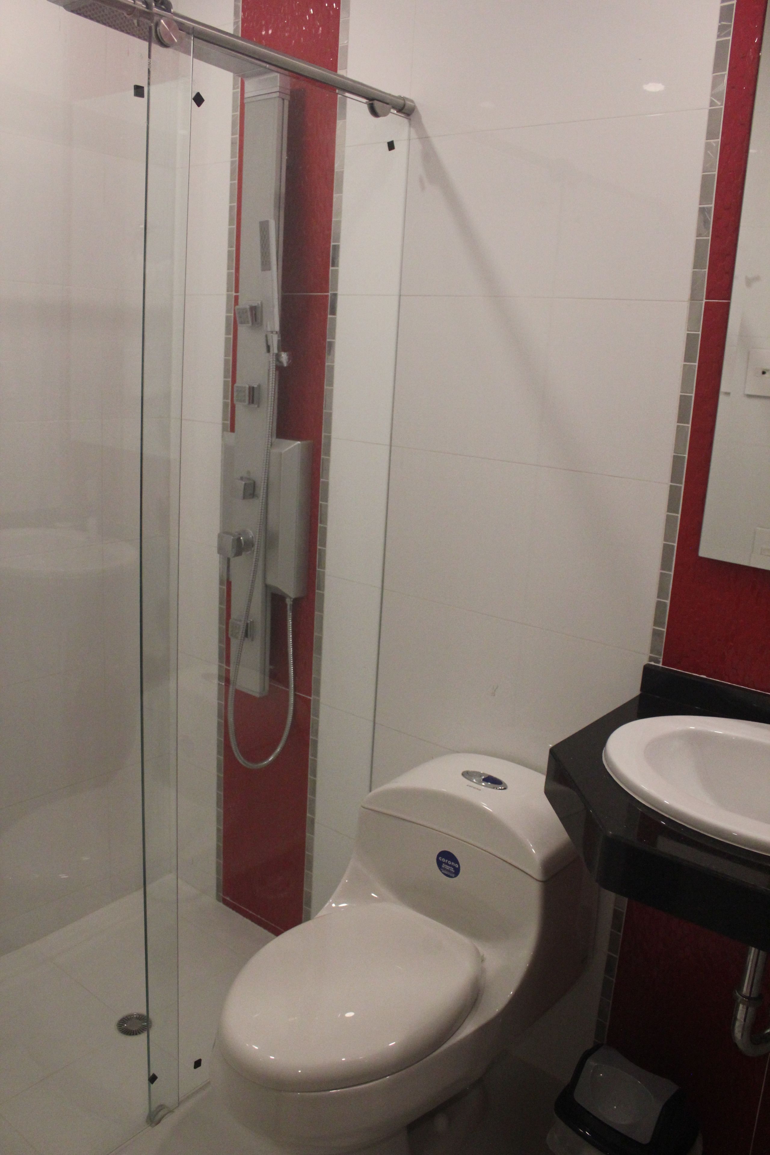 A bathroom with a glass-enclosed shower, a white toilet, and a black sink.