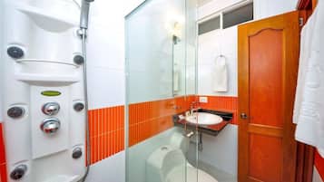 Un baño con ducha de vidrio, inodoro blanco y puerta de madera.