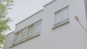 Un hotel llamado "Hotel Palonegro" con una fachada moderna, varios ventanales y una cámara de seguridad en la pared exterior.