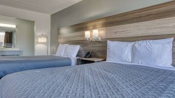 Ein Hotelzimmer mit zwei Betten, einem Holzkopfstück, Nachttischlampen und einem Telefon.