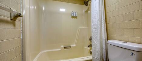 A bathroom with a bathtub, toilet, and a shower curtain.