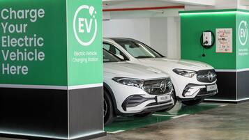 Una estación de carga para vehículos eléctricos con un automóvil blanco estacionado cerca.