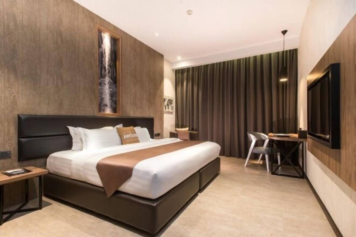 A modern hotel room with a large bed, a desk, and a television.