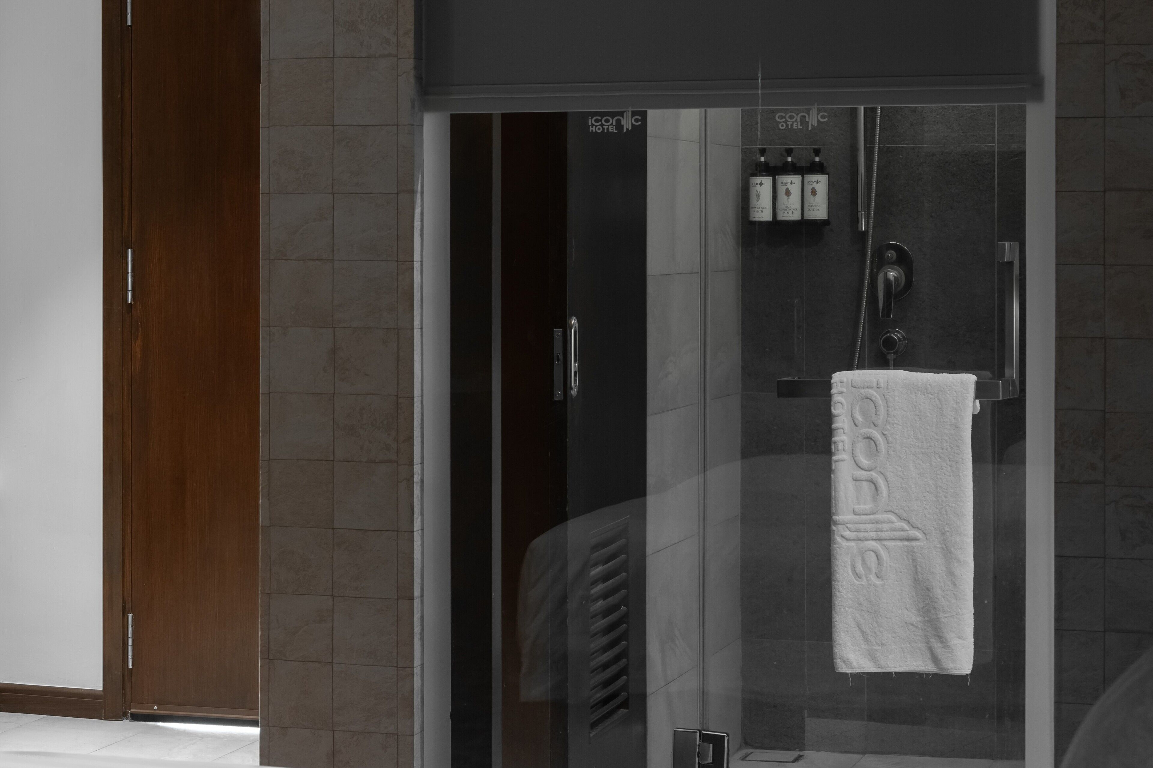 A glass-enclosed shower area with a towel hanging on the door, a showerhead, and a control panel.