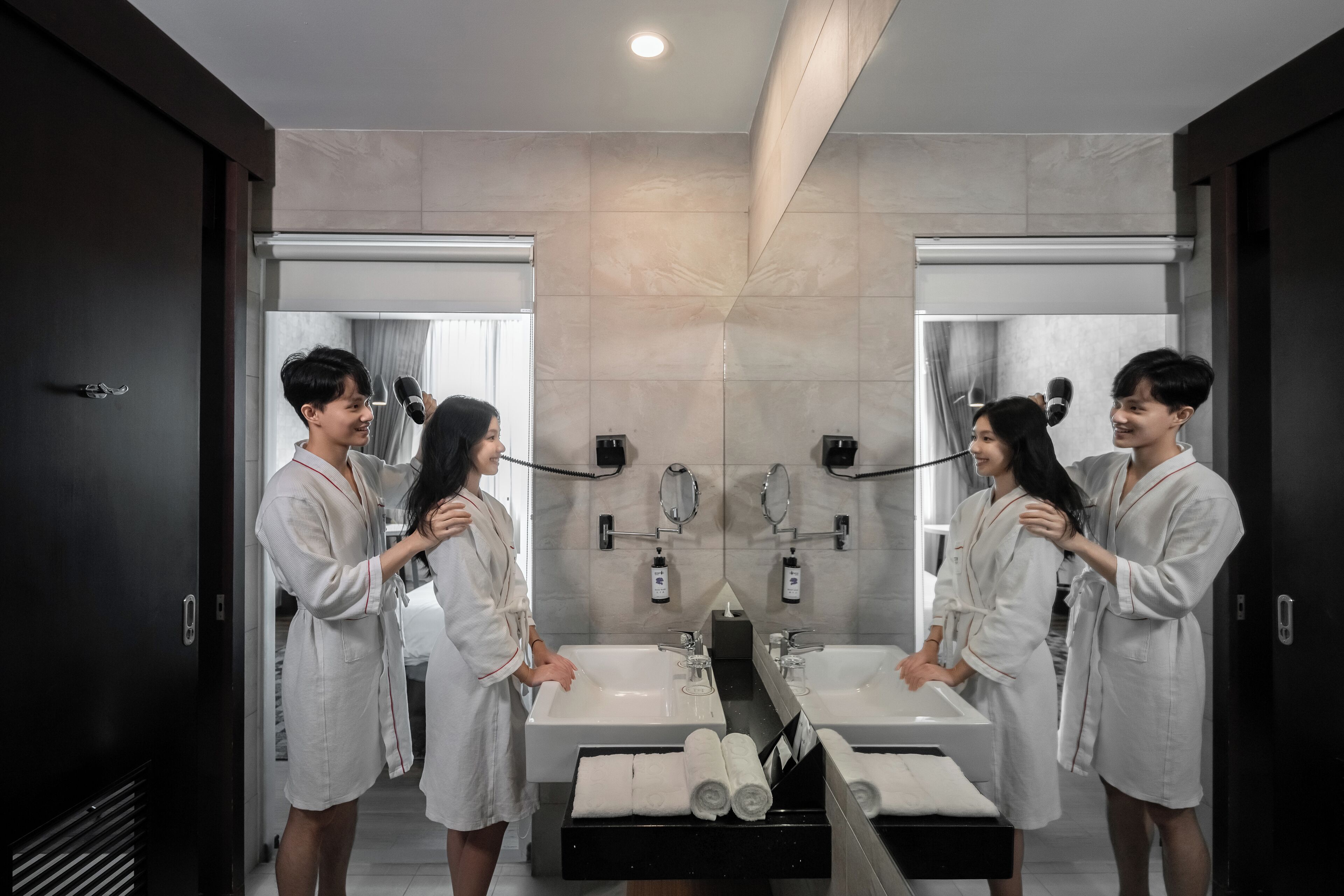 A modern bathroom with two sinks, a large mirror, and a towel rack.