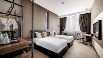 A modern hotel room with two beds, a desk with a coffee maker, a TV, and a wardrobe.