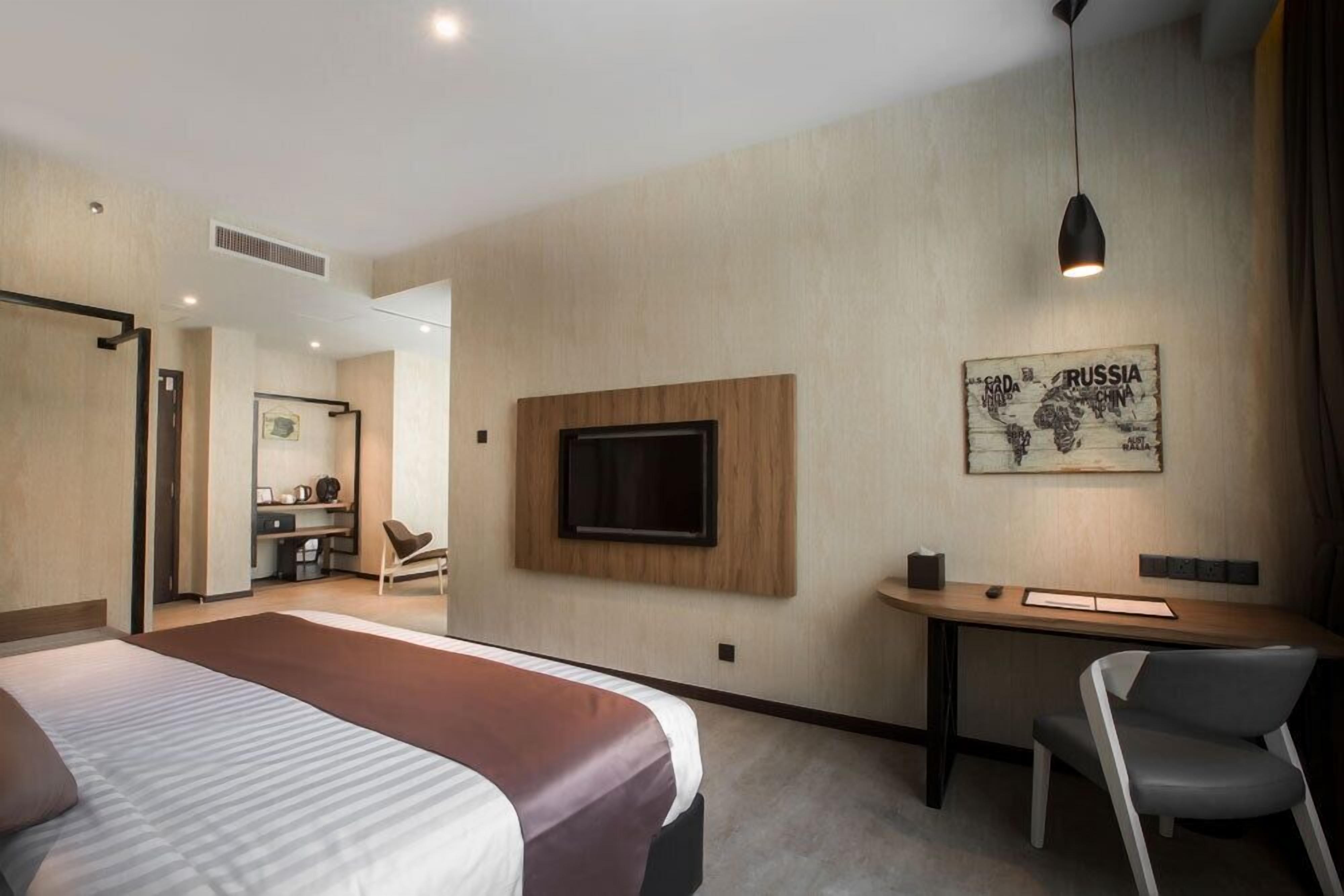 A modern hotel room with a large bed, a desk, and a TV mounted on the wall.