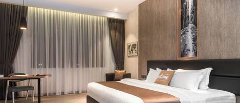 A modern hotel room with a large bed, a desk, and a view of a cityscape through a window.