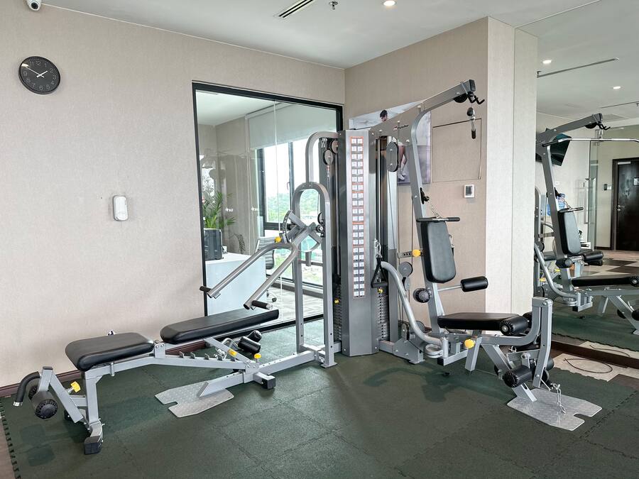 A gym with various exercise machines, a clock, and a large mirror.