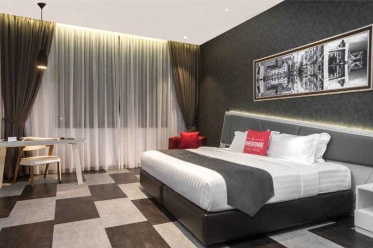 A modern hotel room with a large bed, a desk, and a chair.
