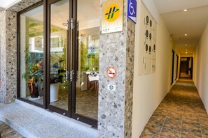 Entrada de hotel con pared de piedra, puerta de cristal y señal que indica zona de estacionamiento para discapacitados.