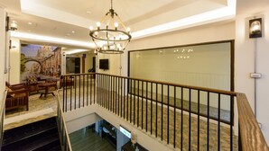 Um hall de hotel com escadas, um candelabro e um espelho grande.