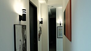 Un pasillo con paredes blancas, obras de arte con marcos negros y una bicicleta colgada en la pared.