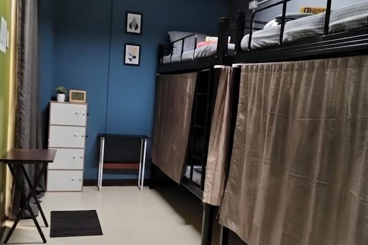 Un dormitorio con camas literas, un escritorio, una silla, un aparador y un equipo de aire acondicionado en la pared.