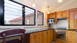A kitchen with wooden cabinets, a stainless steel sink, a microwave, and an oven. - Criterion Hotel Warwick (Warwick)