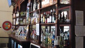 A bar with shelves stocked with various bottles and a dartboard on the wall. - Criterion Hotel Warwick (Warwick)