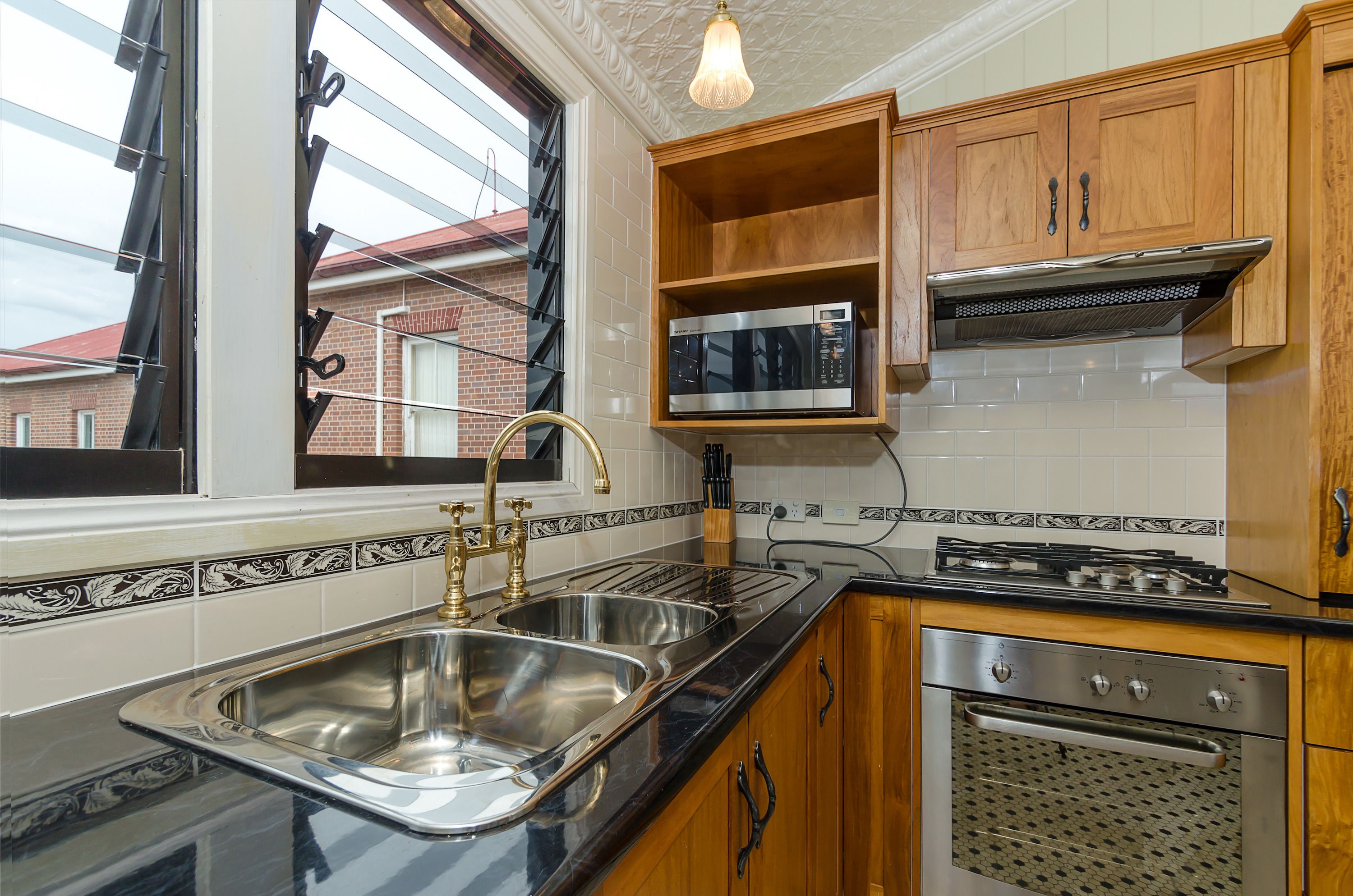 Una cocina con electrodomésticos de acero inoxidable, armarios de madera y un ventanal con vistas a un edificio de ladrillo.
