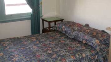 A room with a bed, a small table, and a framed picture on the wall.