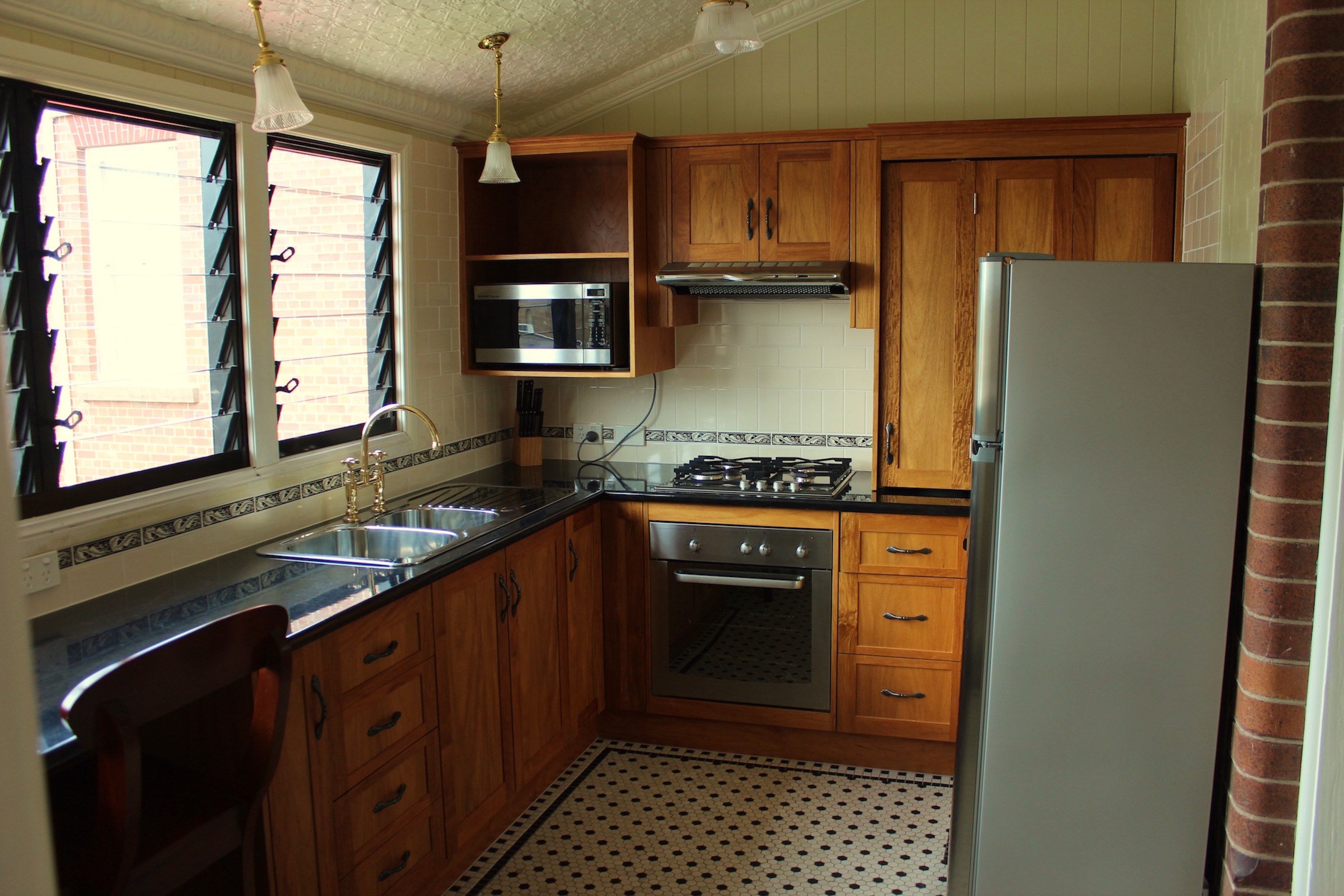 Une cuisine avec des meubles de rangement en bois, un réfrigérateur en acier inoxydable, un four à micro-ondes et une cuisinière à gaz.